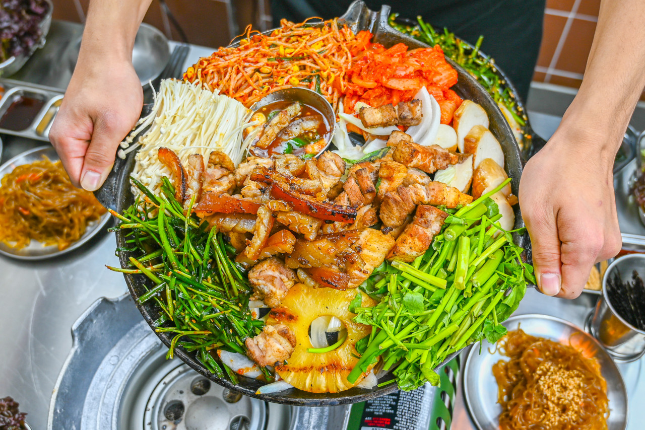 Jinsimdon staff grilling pork for guests over steady heat