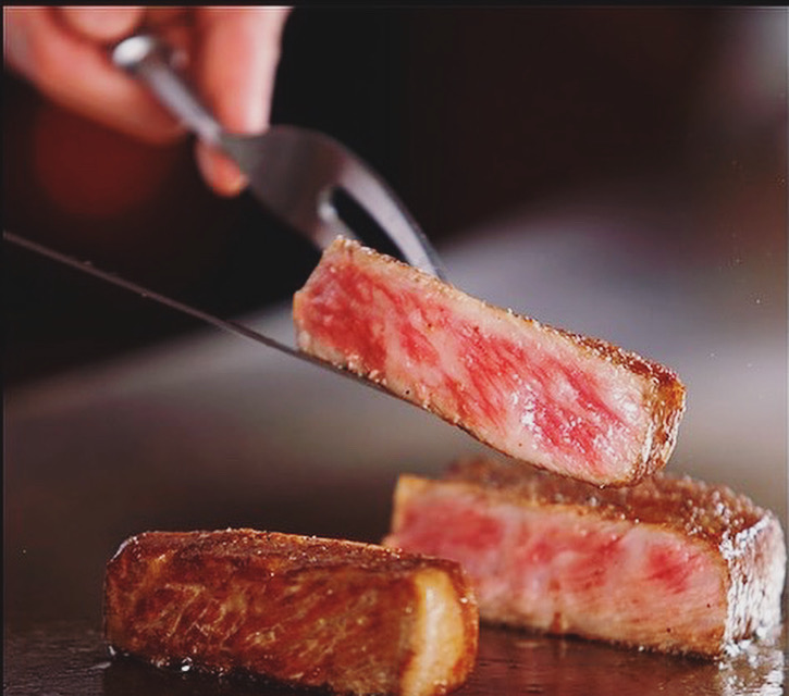 Teppanyaki Takeshi chef searing steak on iron griddle