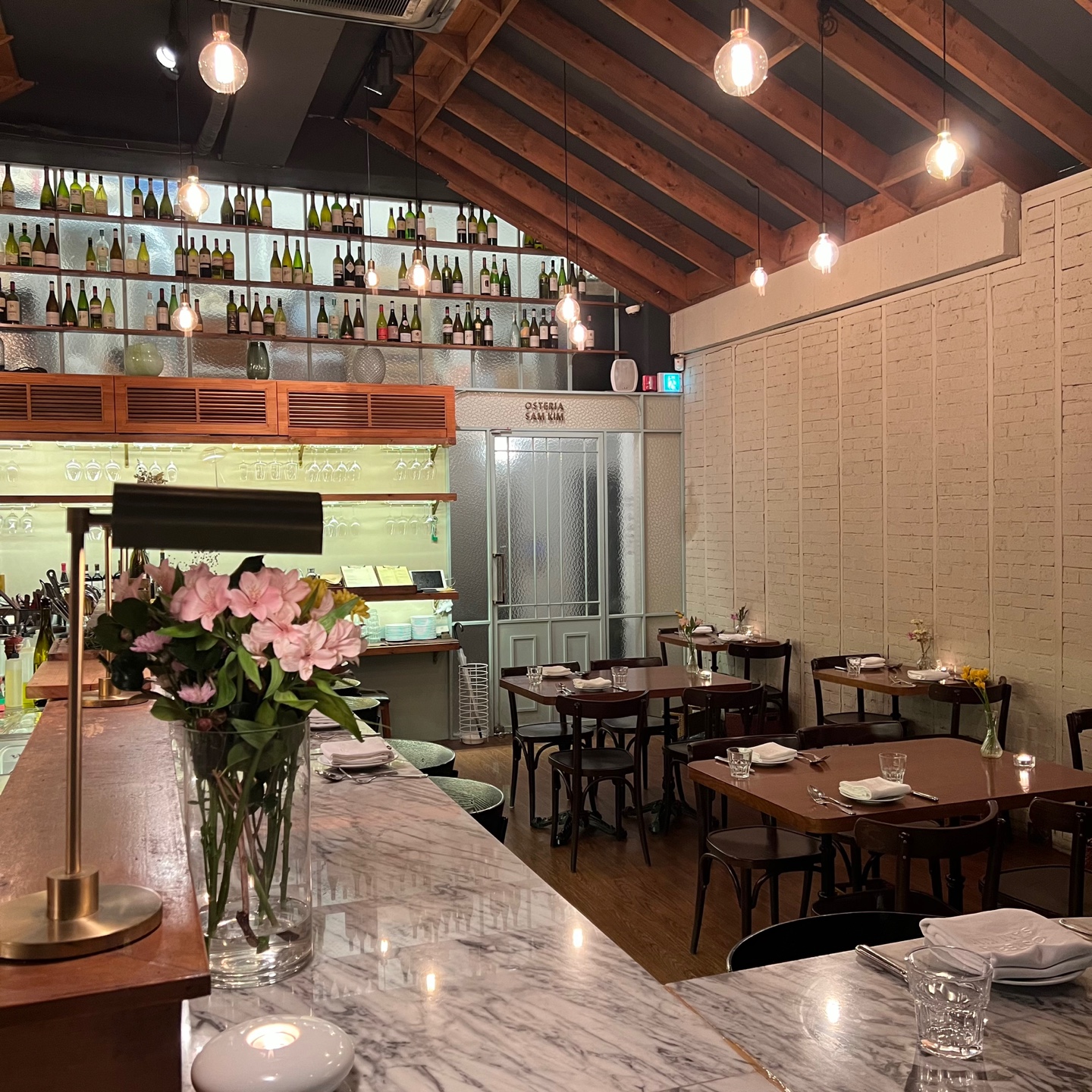 Warm-lit dining room and rustic Italian plates at Osteria Sam Kim - Image 2