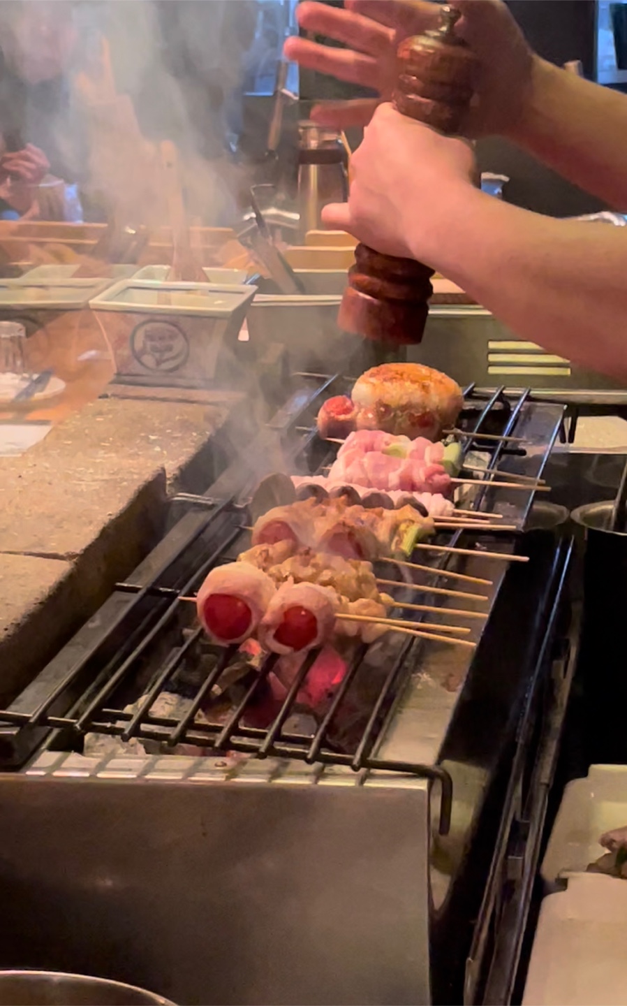 Konyoo’s binchotan-grilled chicken skewers glistening over charcoal