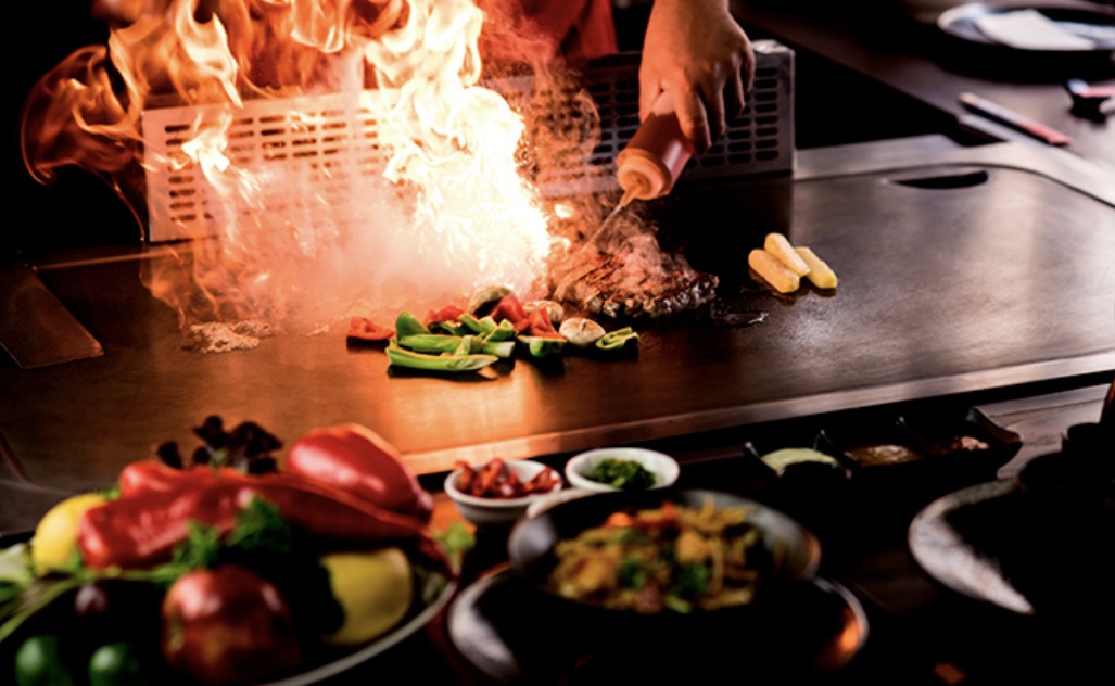 Teppanyaki chef searing on iron griddle at Akemori