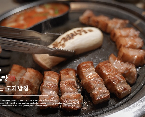 Yukjeon Sikdang staff grilling pork belly with classic banchan
