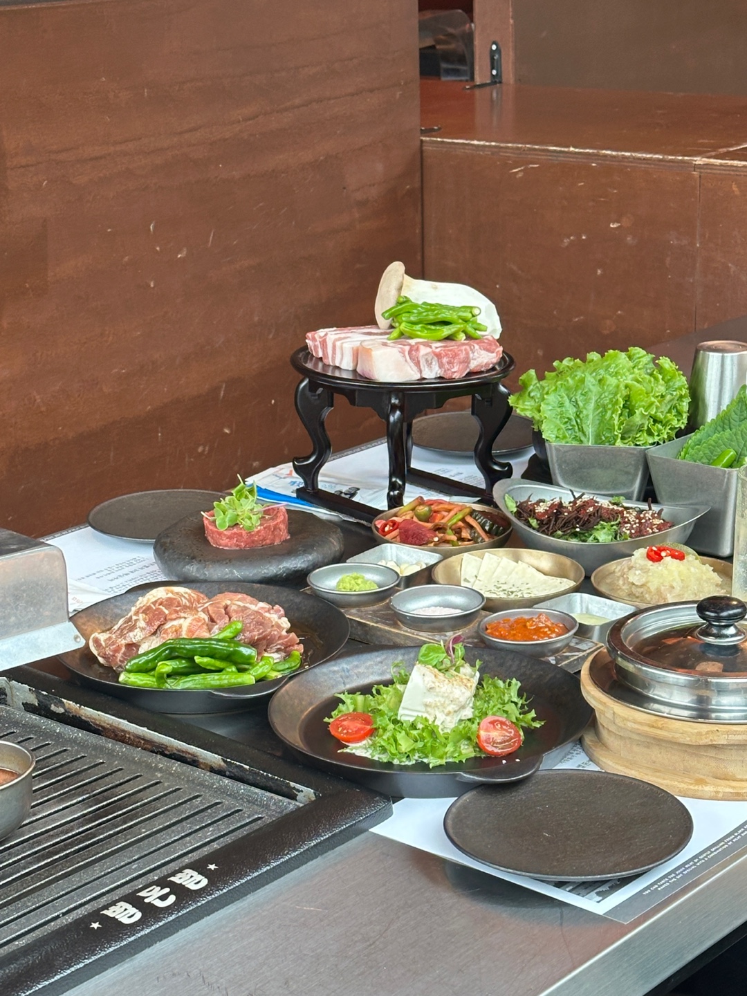 Jeju black pork grilled at BYUL DON BYUL with tangerine trees in the background
