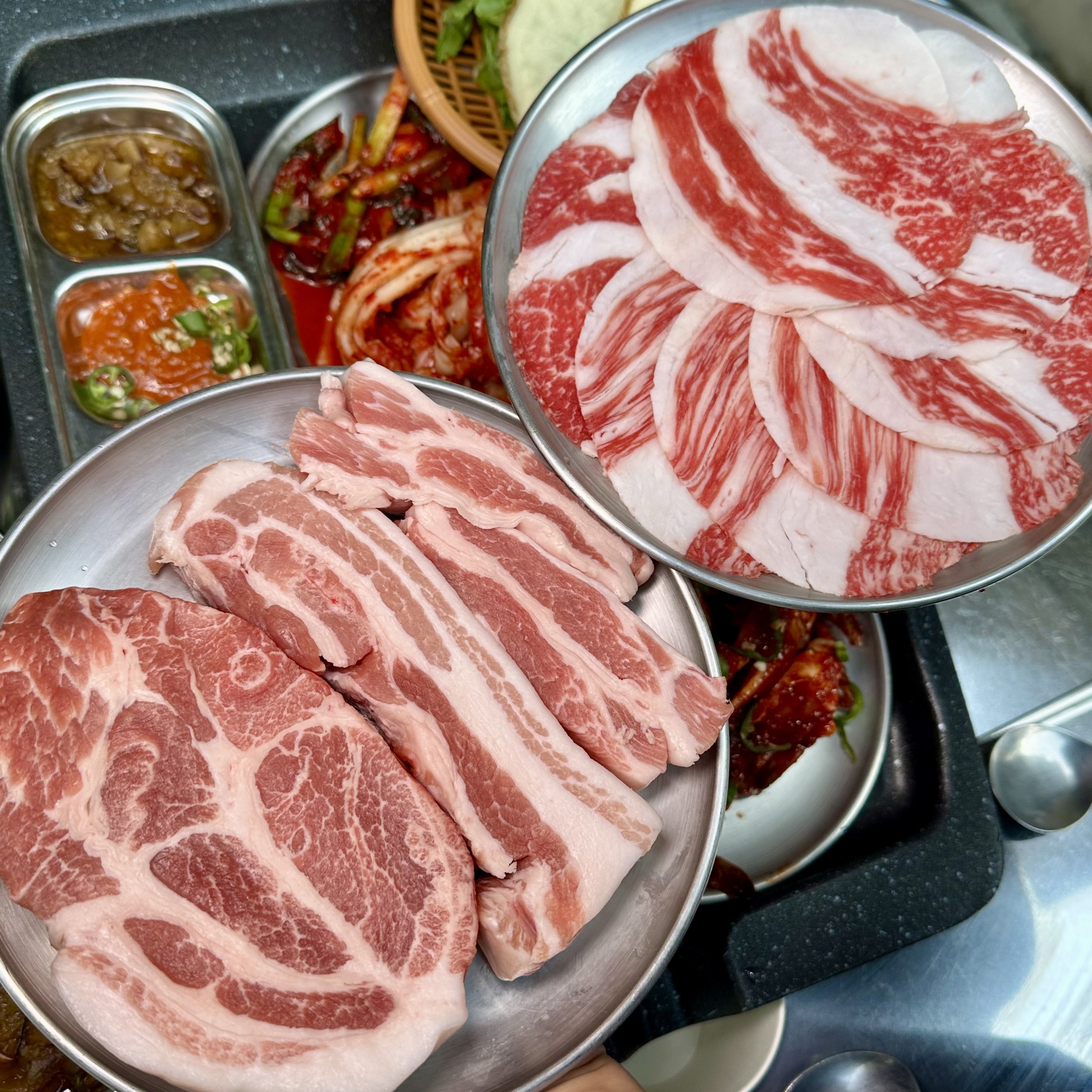 Kim Sukssung 合井店店員於熱金屬烤盤上烤豬五花