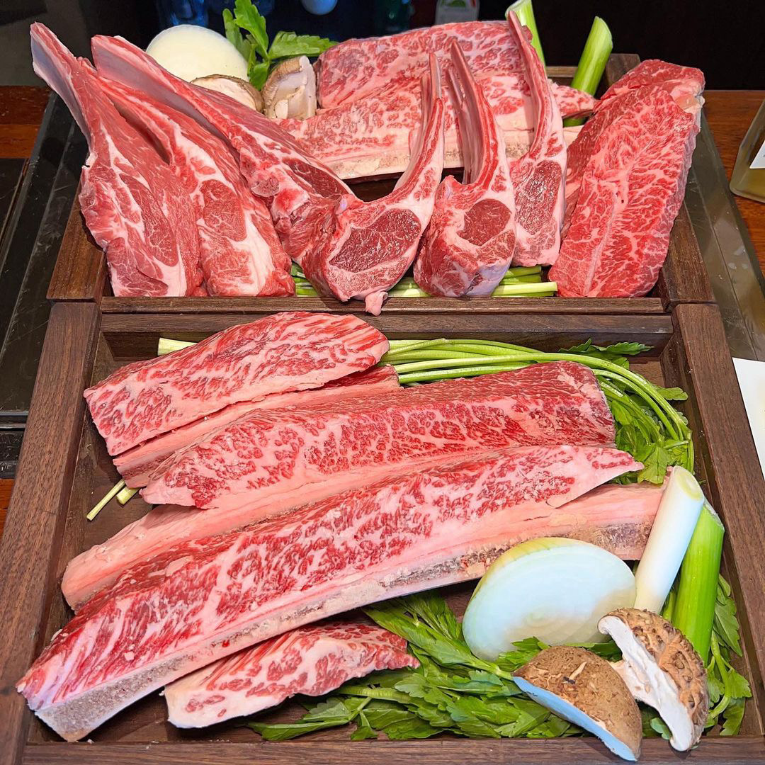 Charcoal grill with marbled beef and lamb chops resting to a glossy sheen